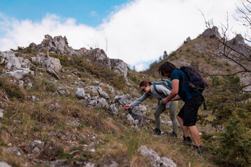 Fototapeta premium Group of friends hiking together on a rocky mountain trail with backpacks, exploring alpine slopes and enjoying an outdoor adventure