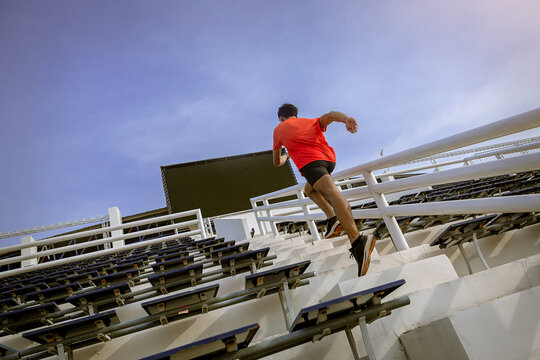 Runners practice stair running to improve their physical strength..Man runner running sprinting up stairs at stadium.