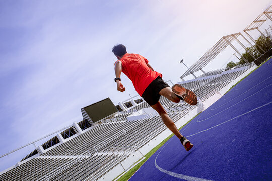 Fit young man running sprinting at the racetrack. Fit runner fitness runner during outdoor workout at racetrack.