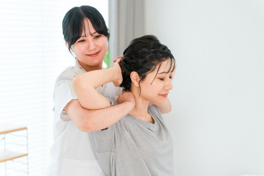A woman gets her neck and shoulders stretched by a massage therapist.