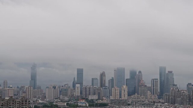 Foggy city skyline with skyscrapers hidden by low clouds