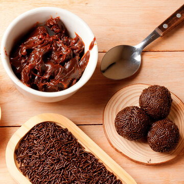 Traditional Brazilian chocolate brigadeiro coated in sprinkles, on a bamboo tray atop a wooden table.