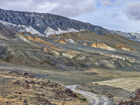 Mountain winding gravel road in the Altai Mountains along the Akkol River valley.