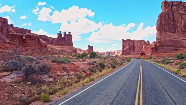 Morning sunlight illuminates towering red rock fins and sandstone formations along the scenic scenic drive in Arches National Park Utah