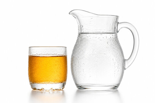 Glass pitcher of water and amber juice glass with condensation, beverage concept