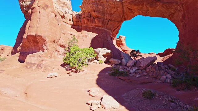 Vibrant evening light illuminates the natural sandstone span of Broken Arch surrounded by desert plains in Arches National Park Utah