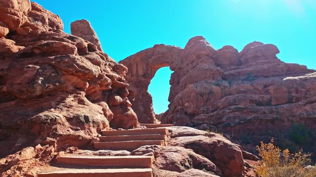Towering natural sandstone arch and adjoining rock spire rise along the scenic Windows loop trail in Arches National Park Utah