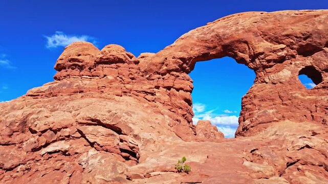 Towering natural sandstone arch and adjoining rock spire rise along the scenic Windows loop trail in Arches National Park Utah