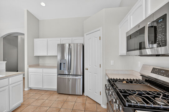White kitchen interior with stainless steel refrigerator oven, microwave, and spacious big cabinetry