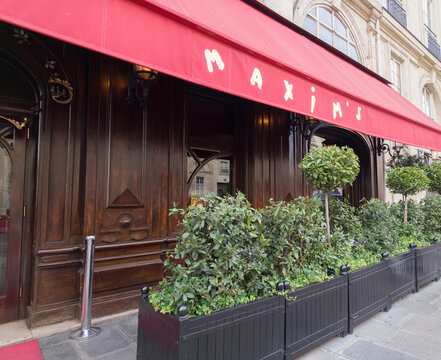 PARIS, FRANCE - SEPTEMBER 1, 2026 - Maxim's restaurant facade in Paris featuring a red awning, wooden doors, and green planters