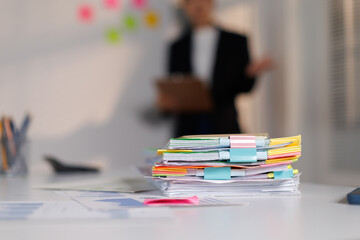 Neatly arranged business documents and paperwork fastened with binder clips on a clean white desk,...