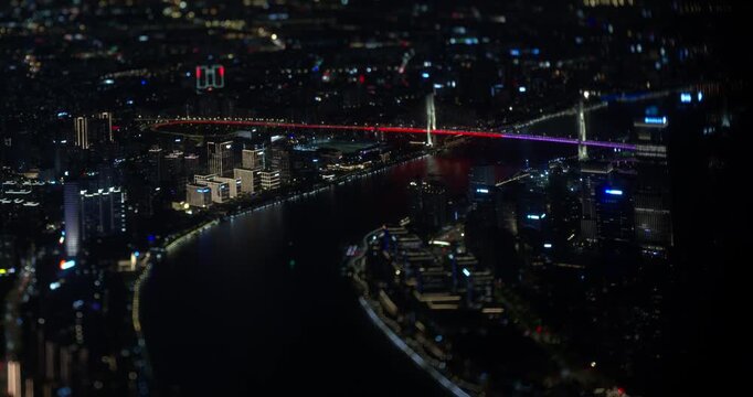 Timelapse captures traffic and lights crossing the Nanpu Bridge over the Huangpu River amid the night cityscape of Shanghai, China, with tilt shift focus
