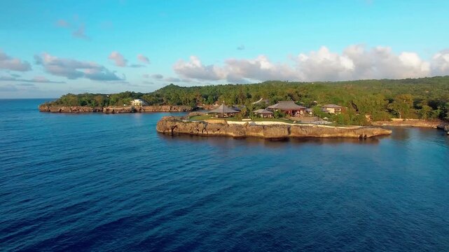 Daytime aerial drone shot flying right over calm ocean waters revealing the luxury Ani private resort peninsula on the rocky coast near R&iacute;o San Juan, Dominican Republic