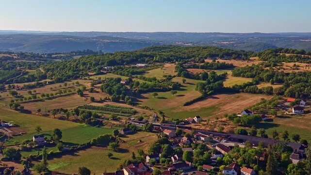 Rural farms, cultivated fields and wooded hills spread across the Ariege foothills near the Pyrenees in Occitanie, France, Europe, revealing the countryside during a drone pullback.