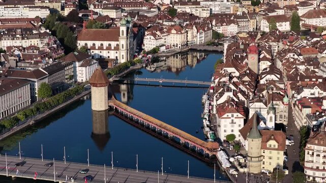 Aerial view of Lucerne, Switzerland, featuring the historic Chapel Bridge and Water Tower crossing the Reuss River, surrounded by the old town and traditional architecture.