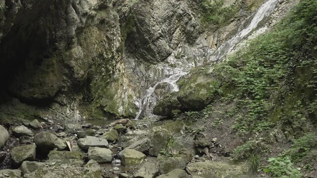 A small cascade flows between steep rock walls at Yeddi Gozel in Gabala in soft daylight.