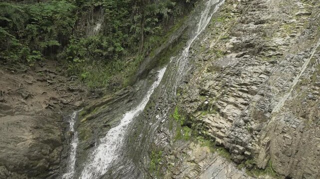 A closer view follows water across layered rock at Yeddi Gozel Waterfall in Gabala in daylight.