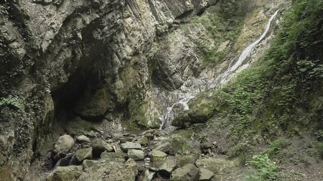 A rocky gorge surrounds a cascading stream below Yeddi Gozel Waterfall in soft daylight.