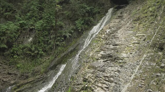 Water runs down a broad sloping rock face at Yeddi Gozel Waterfall in Gabala in daylight.