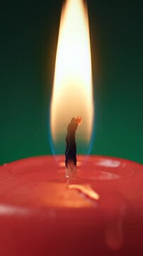 Merry christmas red candle burning on wood table with green backdrop