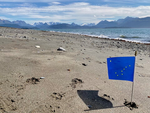 Alaskan flag on beach near ocean and mountains at Homer Spit, Alaska