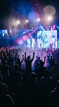 Modern church worship night event with diverse crowd praising God under stage lights.