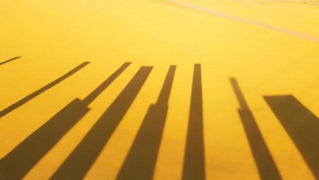 Shadows of vertical objects on a bright yellow surface