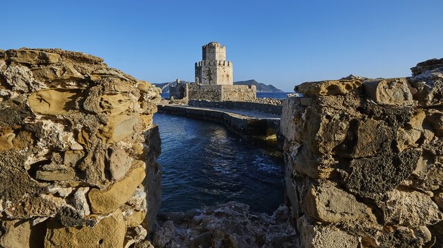 View through a crumbling bridge to a castle by the sea under a deep blue sky, octagonal medieval tower. Islet of Bourtzi, sea fortress of Methoni, Peloponnese, Greece