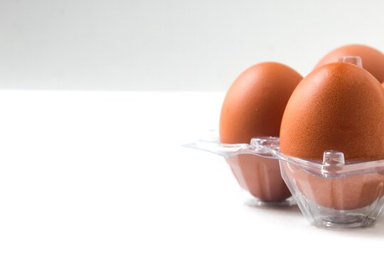 fresh chicken eggs in a plastic tray on white background with copy space