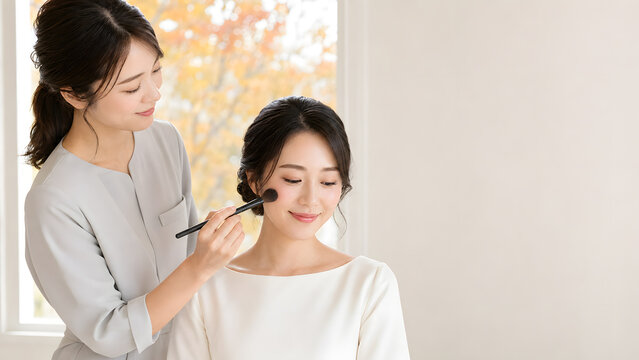 結婚式前にメイクアップアーティストから化粧を受ける花嫁