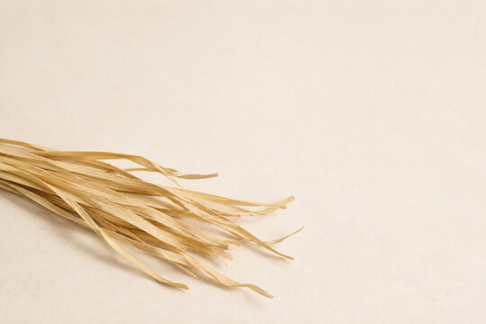 Loose Natural Raffia Strips on a Warm Ivory Surface