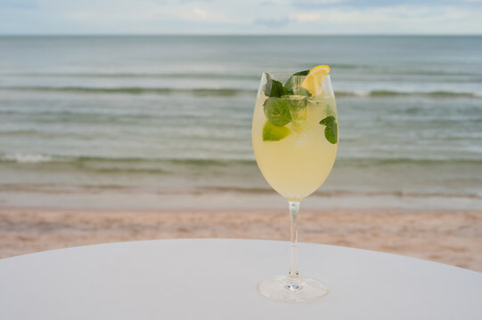 Yellow cocktail with lemon on a table at the beach.