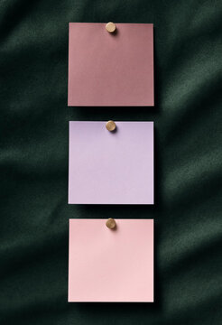 Three pastel sticky notes pinned on dark green velvet fabric background