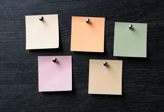 Pastel sticky notes on dark wooden background, flat lay office stationery for reminders.