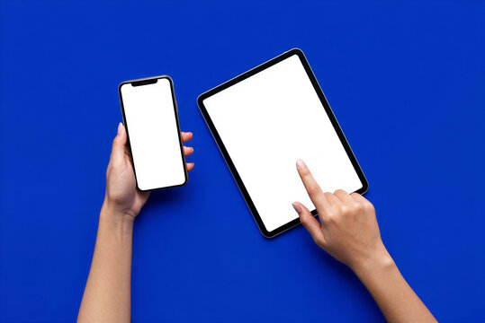 Hands holding smartphone and tablet with blank white screens on blue background