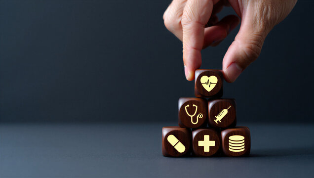 Hand stacking wooden cubes with medical icons for healthcare and insurance concept.