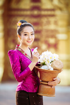 Radiant smiles and timeless traditions. A beautiful Lao girl dressed in traditional attire, ready for the morning alms-giving ritual. Perfect for travel and culture campaigns.