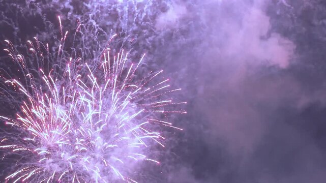 Colorful bright fireworks exploding in the night sky during celebration.