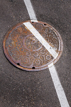 Man Hole Manhole Cover Made of Iron Worn and Rusty with Painted White Line for Street on Aspalt Marking Skewed Position