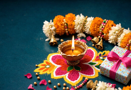 Traditional Diwali celebration with colorful rangoli oil lamp flowers and gift box on dark background