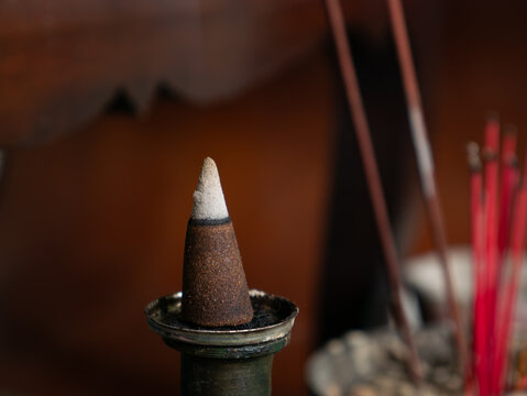 Incense Cone Burning with Smoke and Red Joss Sticks on Shrine, Buddhist Ritual Close-Up