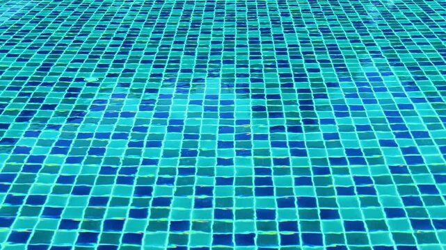 Clear water rippling over blue mosaic tiles in a swimming pool background.