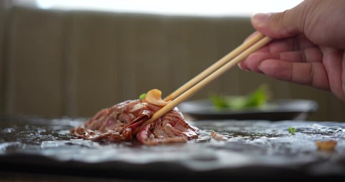 A man use chopsticks eating A5 grade Japanese wagyu beef sushi.