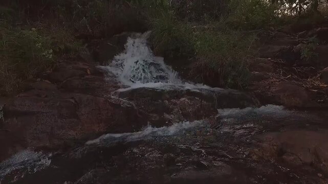 Loquinhas Waterfall rushes over smooth ancient rock formations in Alto Paraiso de Goias, Goias, Brazil, South America, within Chapada dos Veadeiros, extreme close-up FPV drone forward flyover.
