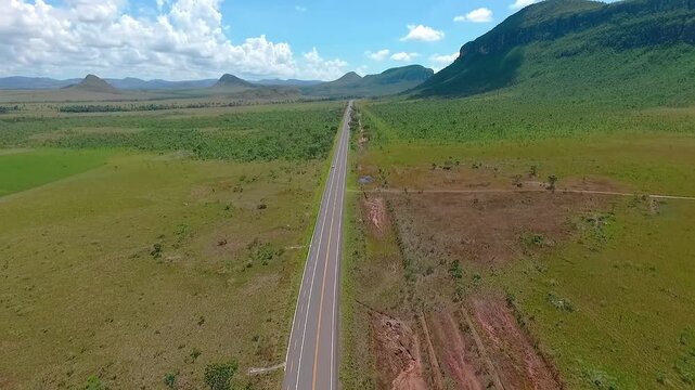 GO-239 crosses beside Morro da Baleia in Alto Paraiso de Goias, Goias, Brazil, South America, through the Chapada dos Veadeiros Cerrado and broad plateau terrain, drone pullback.