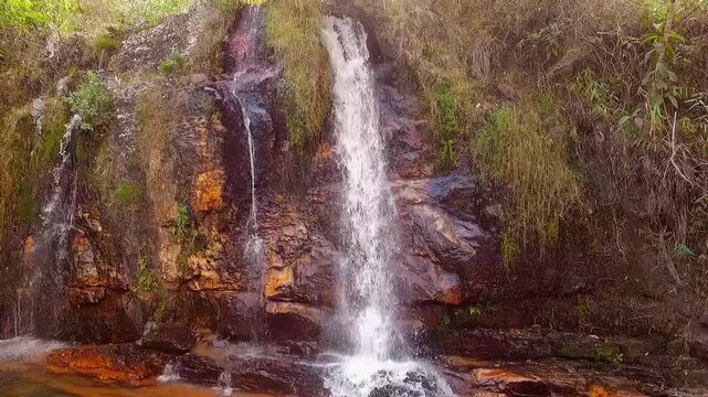 Loquinhas Waterfall cascades over reddish rock into a clear pool in Alto Paraiso de Goias, Goias, Brazil, South America, within Chapada dos Veadeiros, static shot.