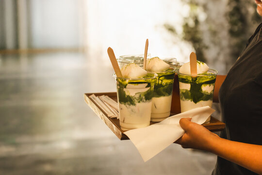 Waiter serving a matcha drinks on wooden tray in cafe.