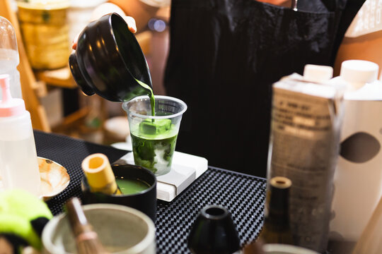 Barista pouring green matcha tea in a take away glasses with iced.
