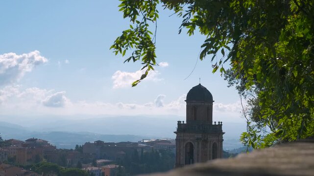 Scenic italian cityscape with bell tower and green leaves. Beautiful panoramic view of a historic italian city with a traditional bell tower, seen from a high vantage point
