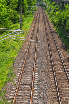 Electrified Double Railway Tracks Curving Through Green Woodland